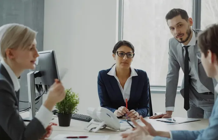 Group of professionals discussing plans around a desk in a bright office, suitable for mapping business contacts